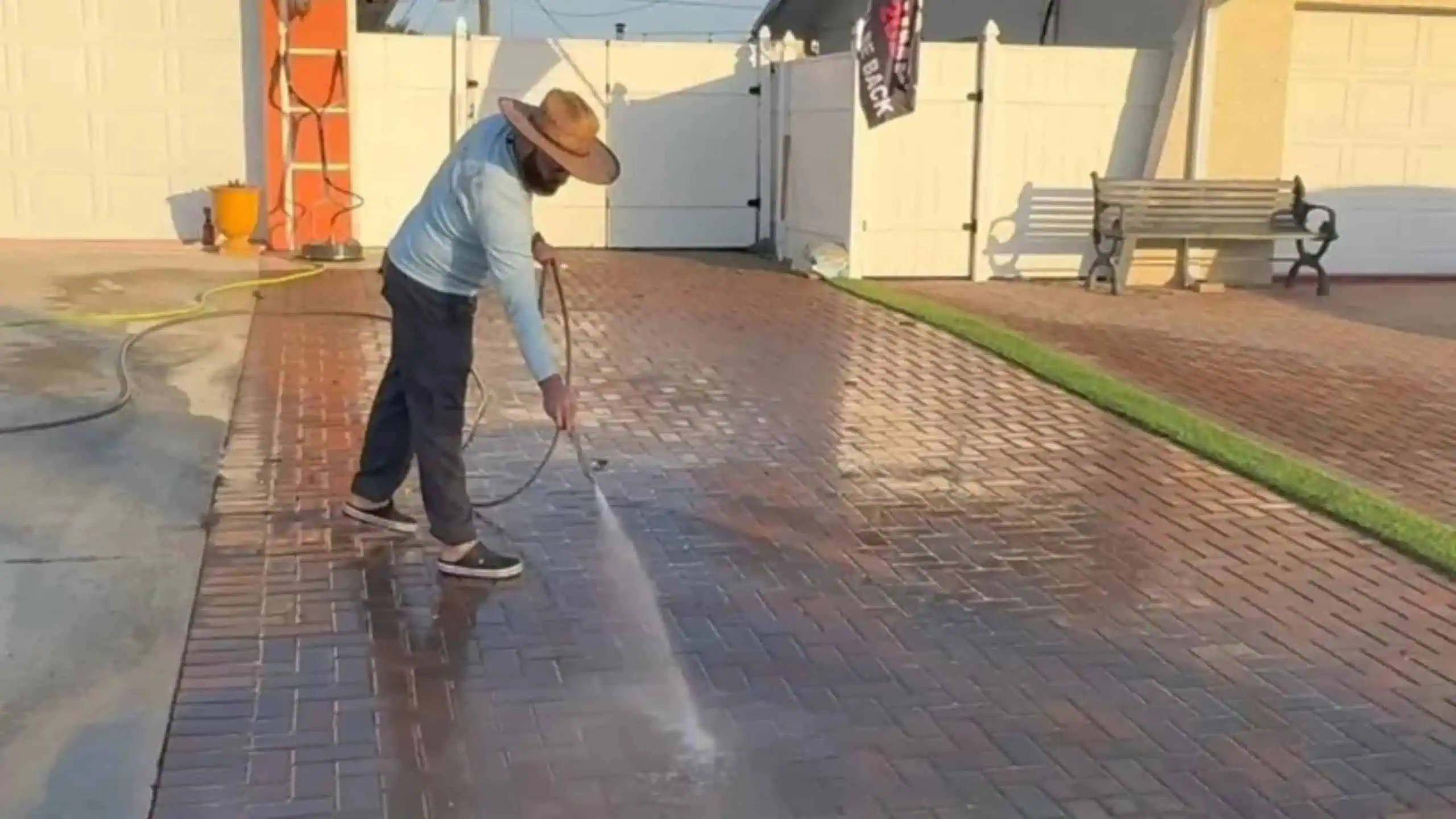 "a man providing paver sealing services using a pressure washer to clean pavers before sealing the surface"