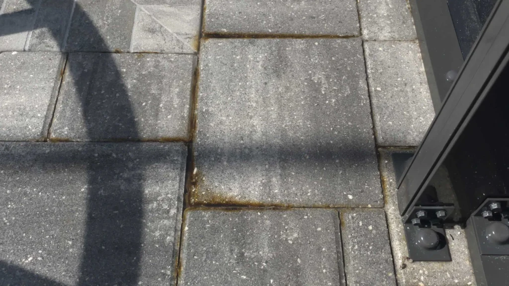 "rust stains on pool pavers from a leak on the lanai enclosure"